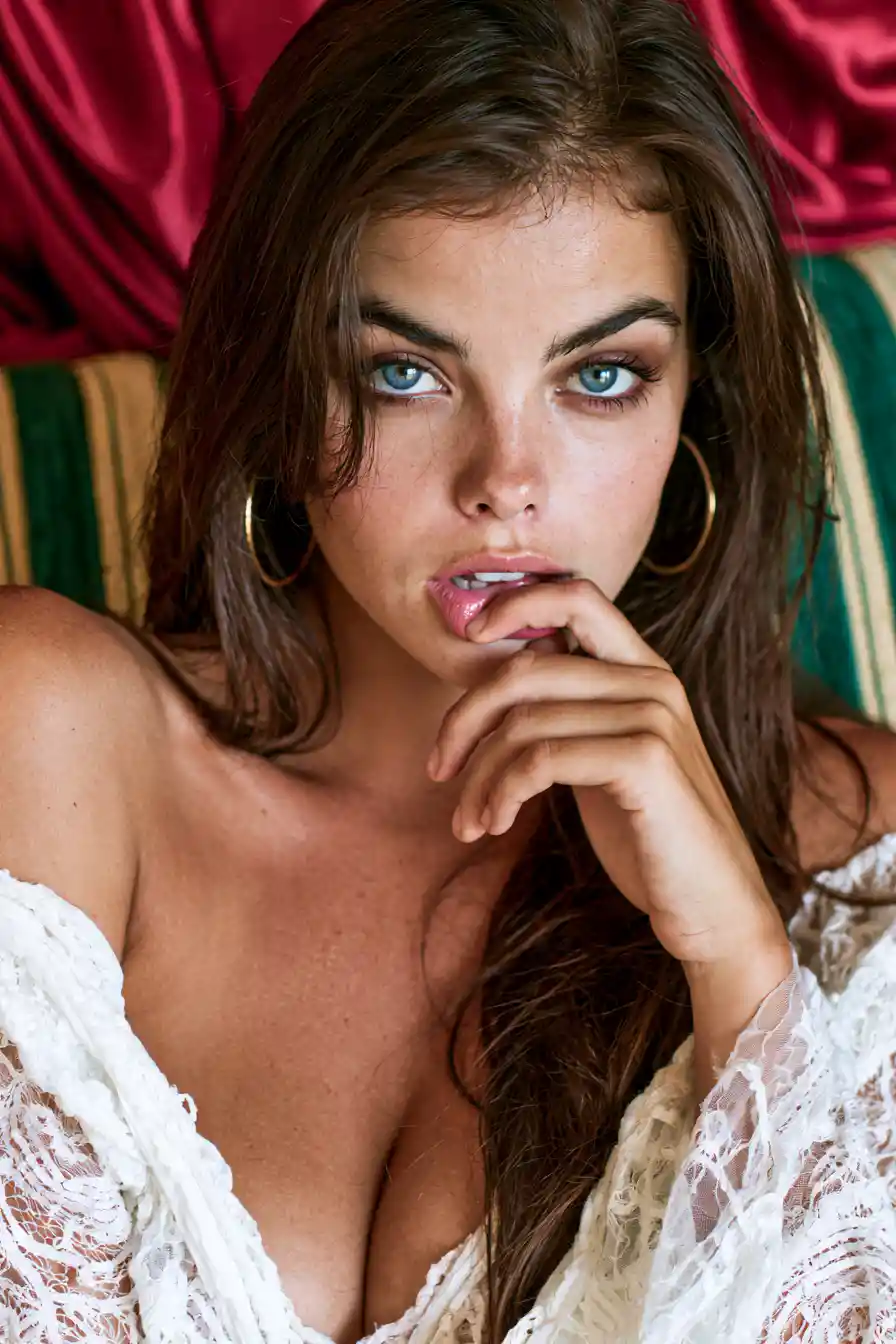 Young woman in lace blouse against red satin background