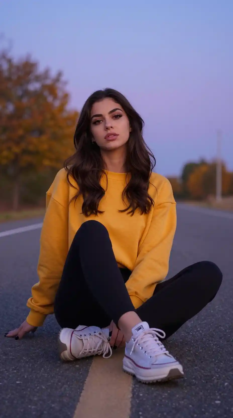 Young woman sitting cross legged on an autumn road