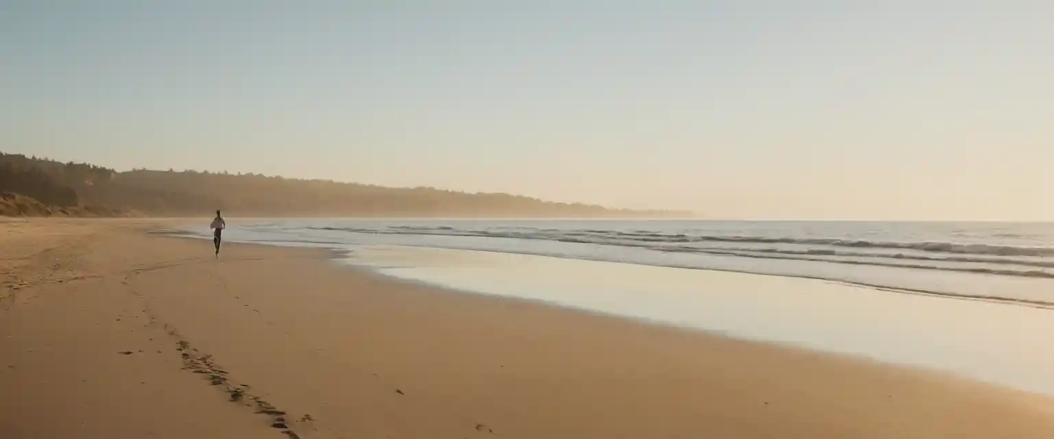 Lone woman jogging along a tranquil beach at sunset