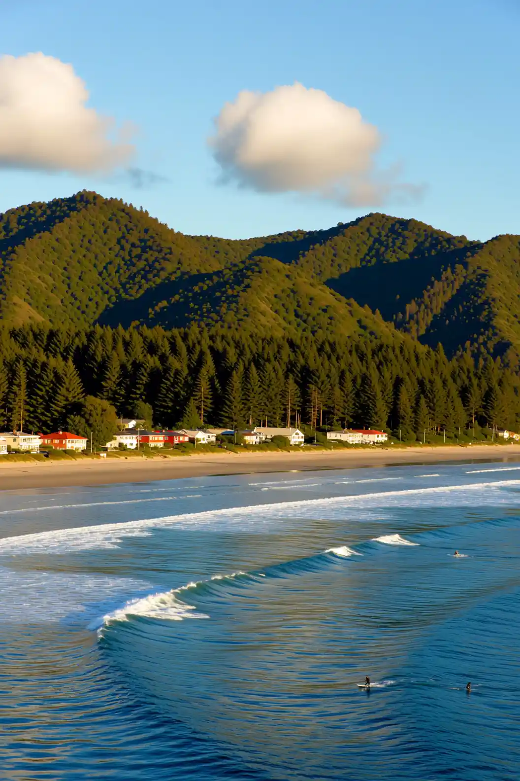 Peaceful seaside village with surfers and green forest hills