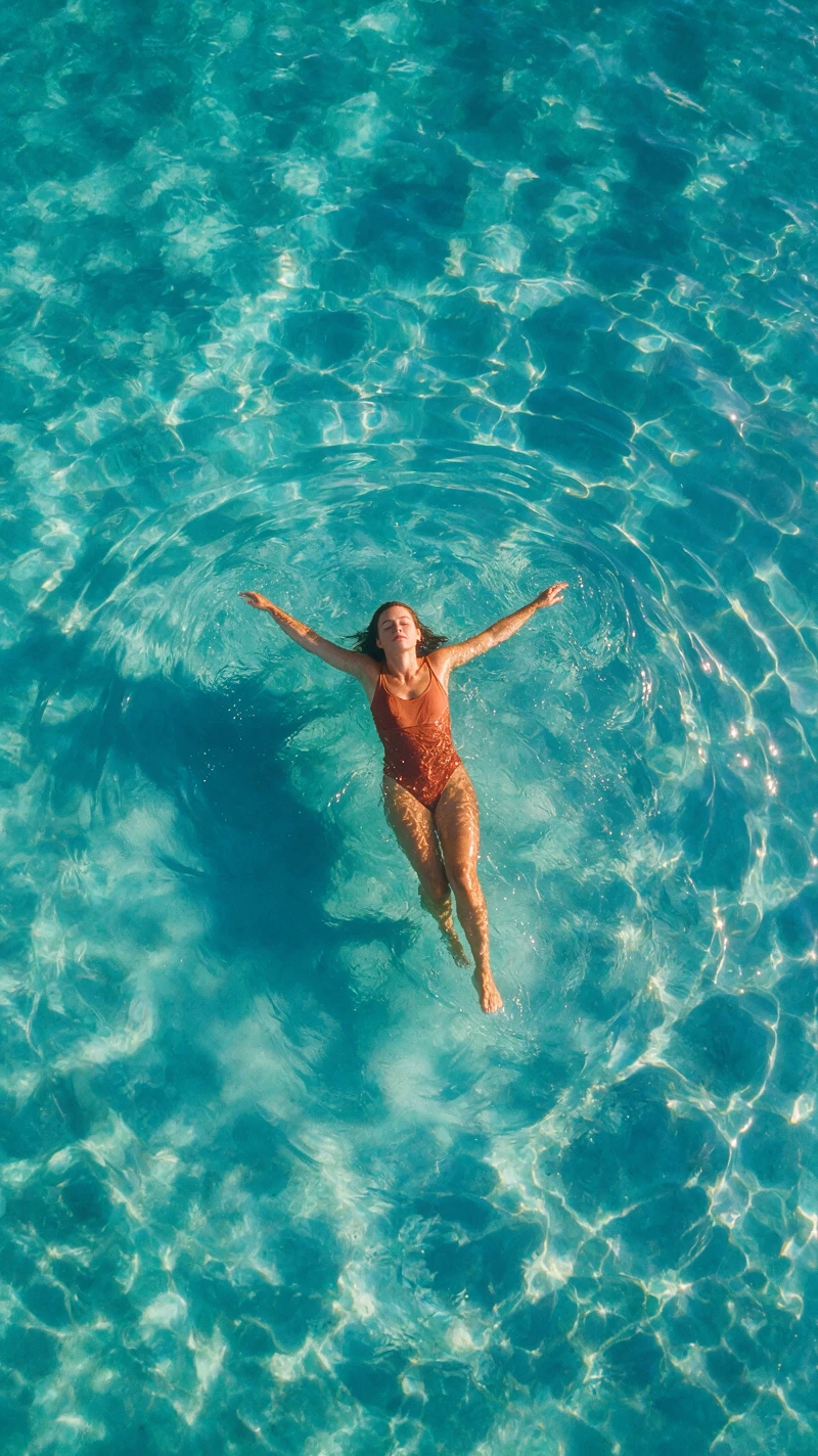 Mujer flotando en un océano turquesa durante una tranquila hora dorada