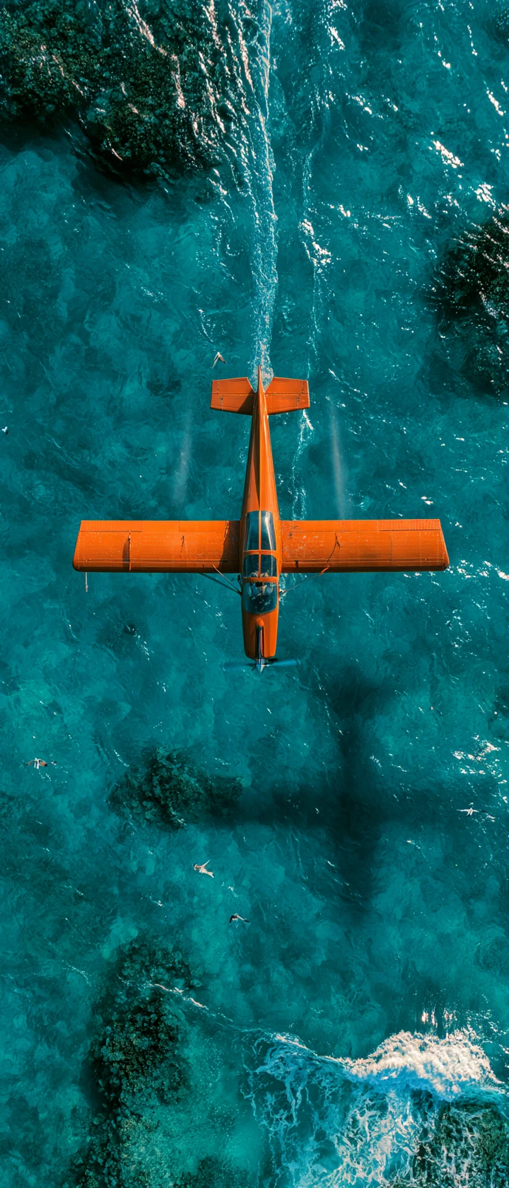 Avión vintage naranja volando sobre un océano turquesa