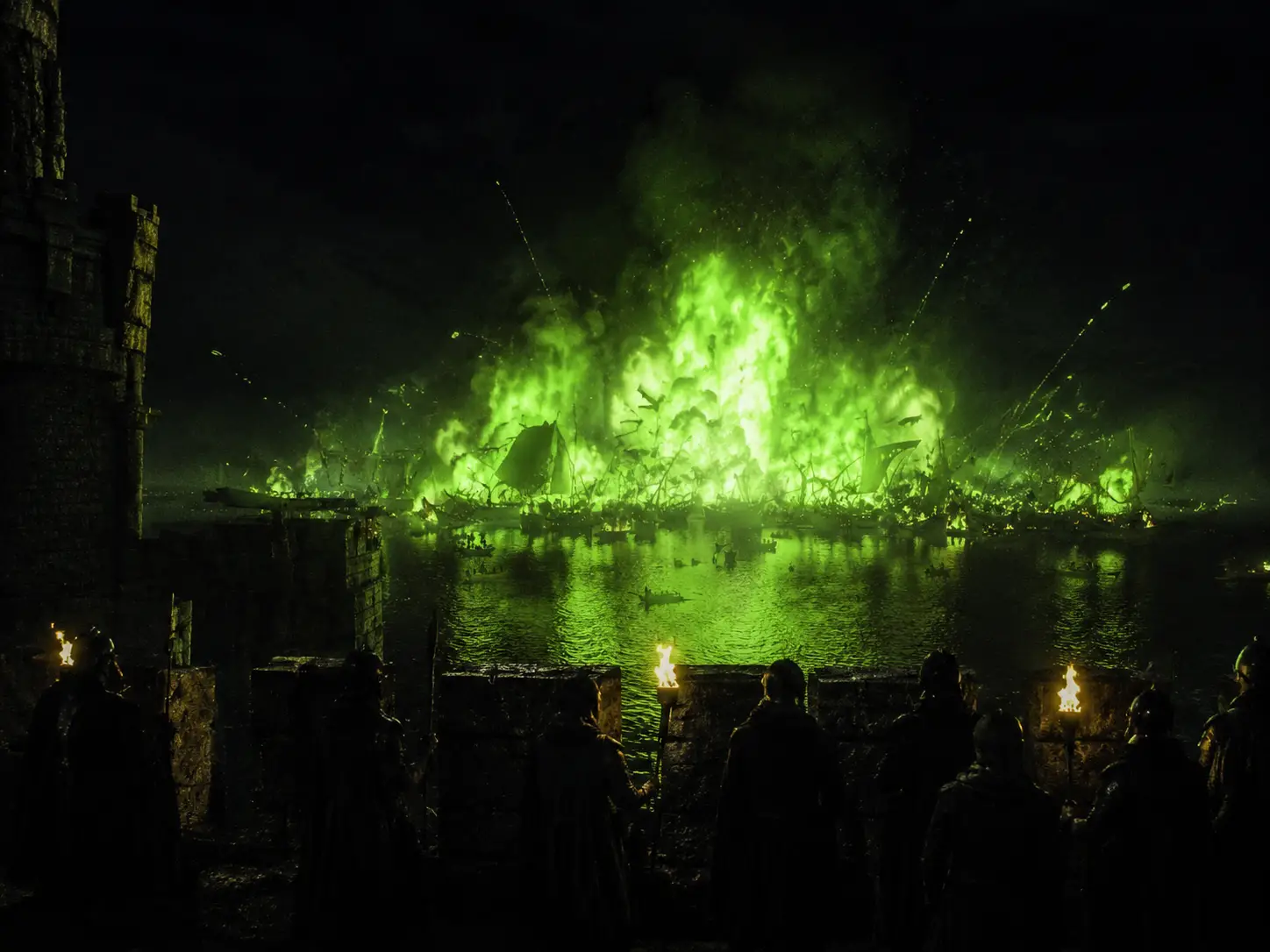 Medieval battlements overlook ships burning on dark water