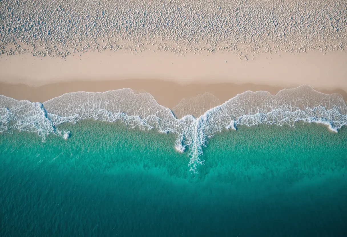 Aerial view of white sand beach and turquoise sea at sunset