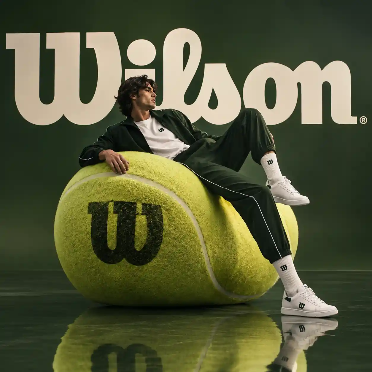 Male athlete reclining on a giant tennis ball sculpture