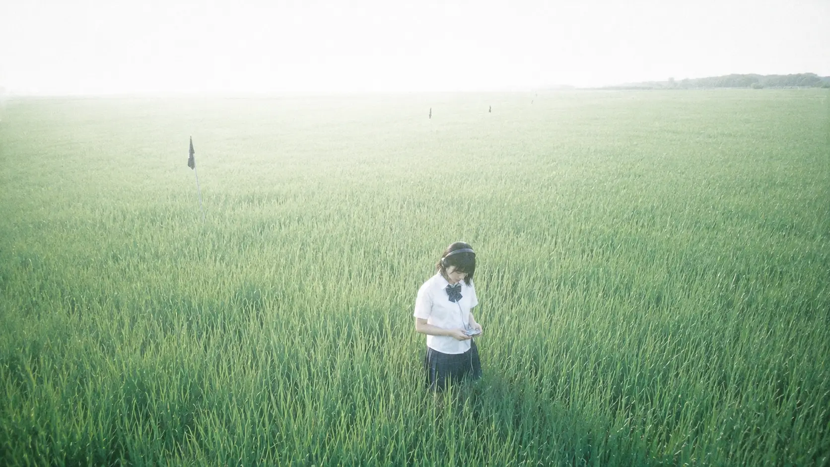 Teenage girl in rice field with headphones and discman