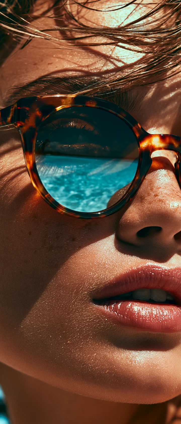 Mujer bronceada con gafas de sol carey junto a un mar turquesa