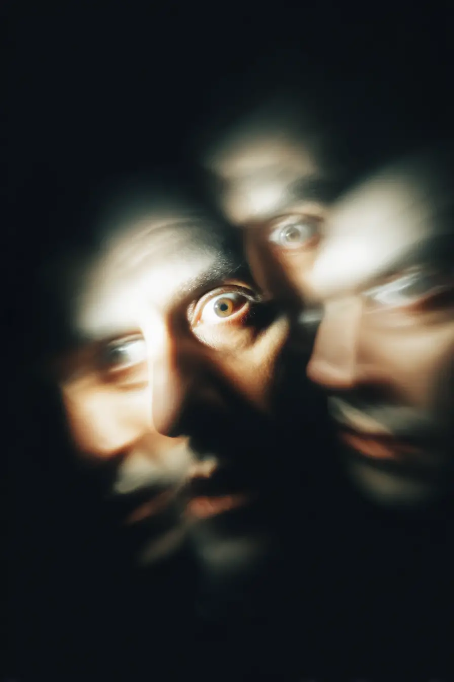 Blurred face fading into darkness with unblinking eyes