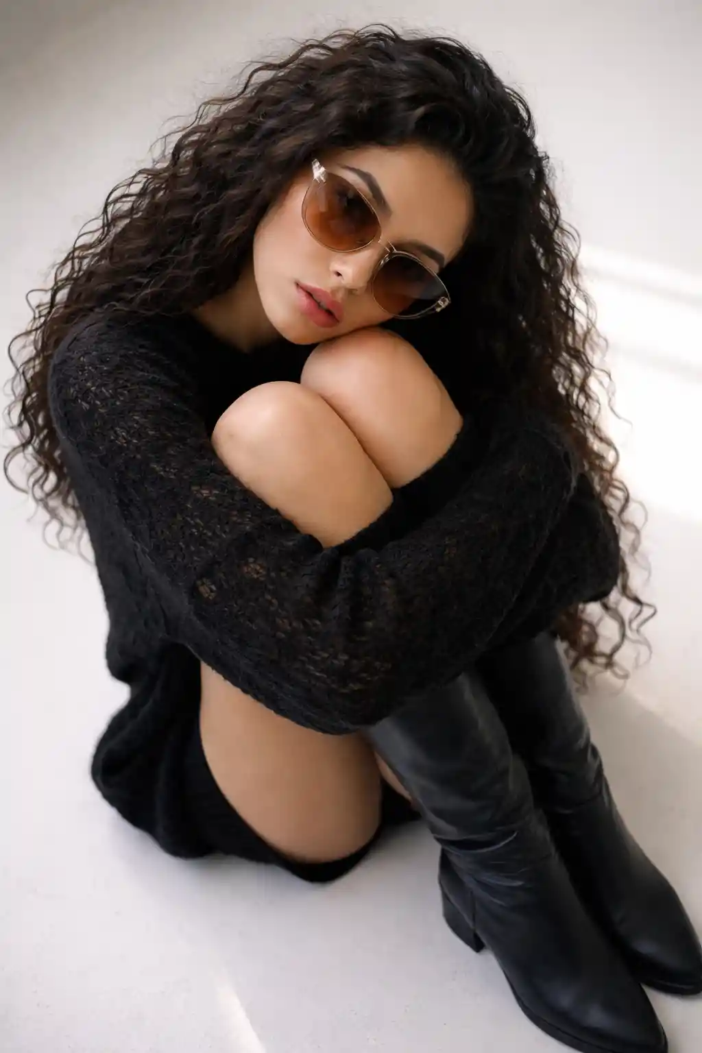 Top down portrait of woman in sunglasses on white floor