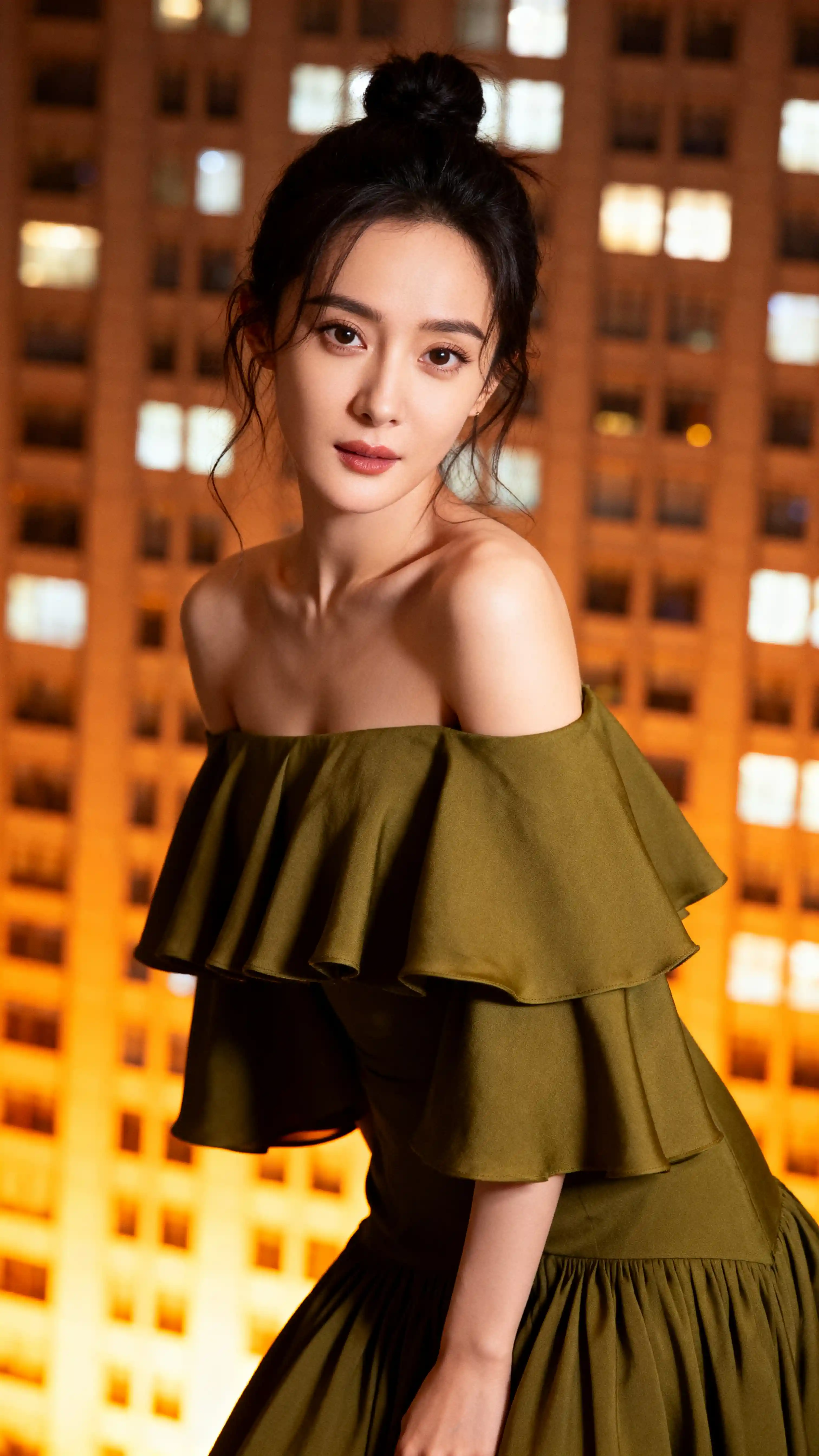 黃昏時分在都會高樓窗邊擺姿的時尚女子