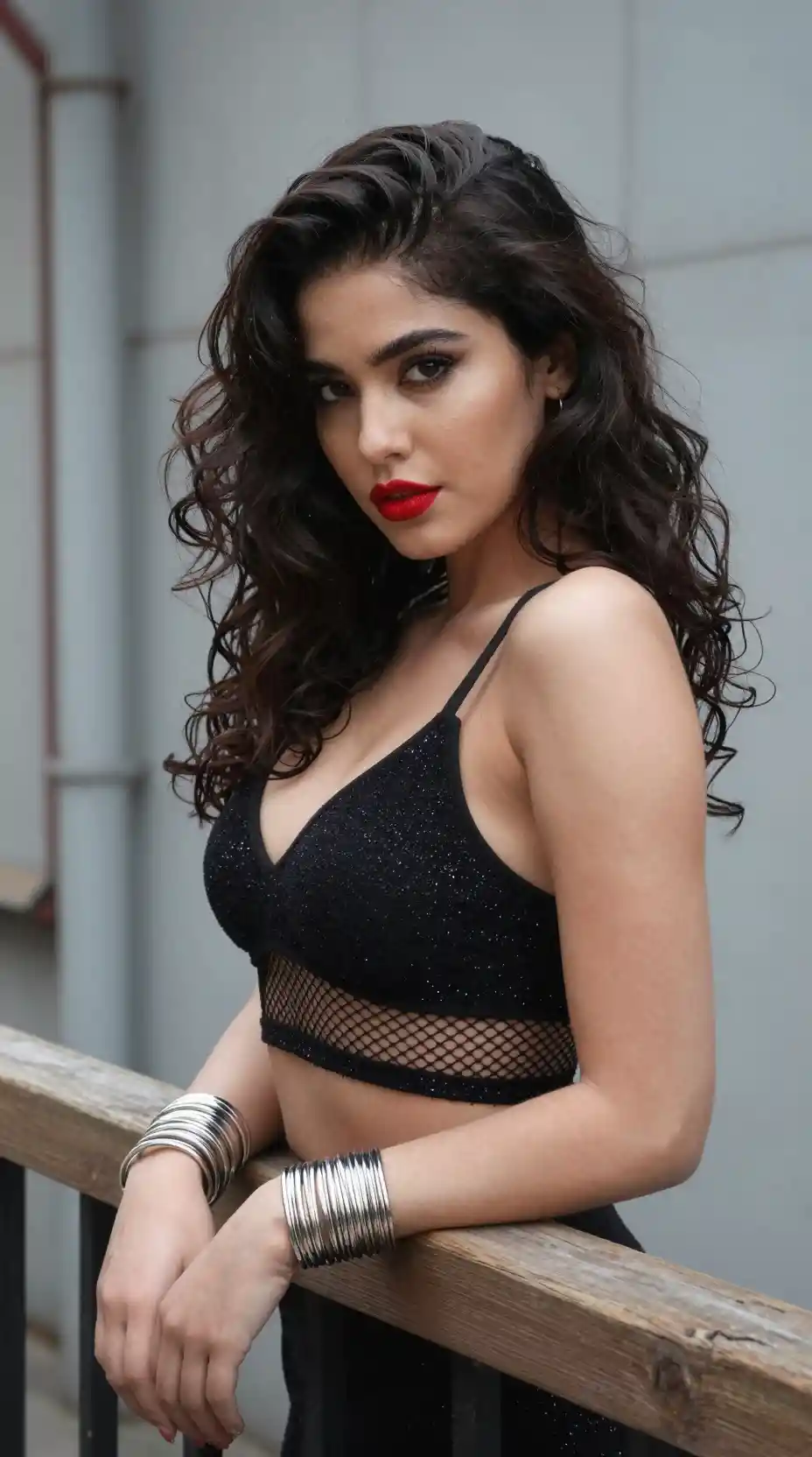Mujer confiada con top corto negro junto a baranda industrial