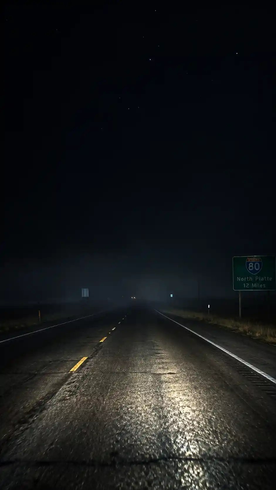 Autoroute solitaire la nuit éclairée par les phares lointains d’une voiture