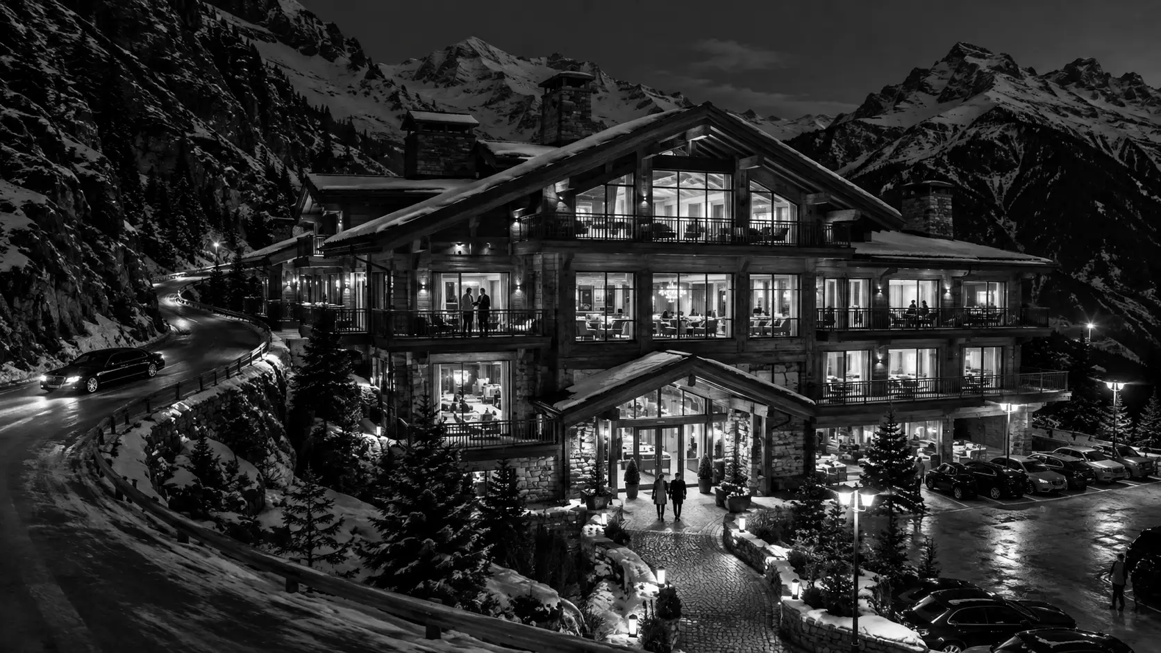 A Swiss chalet resort glows above a winding mountain road at night