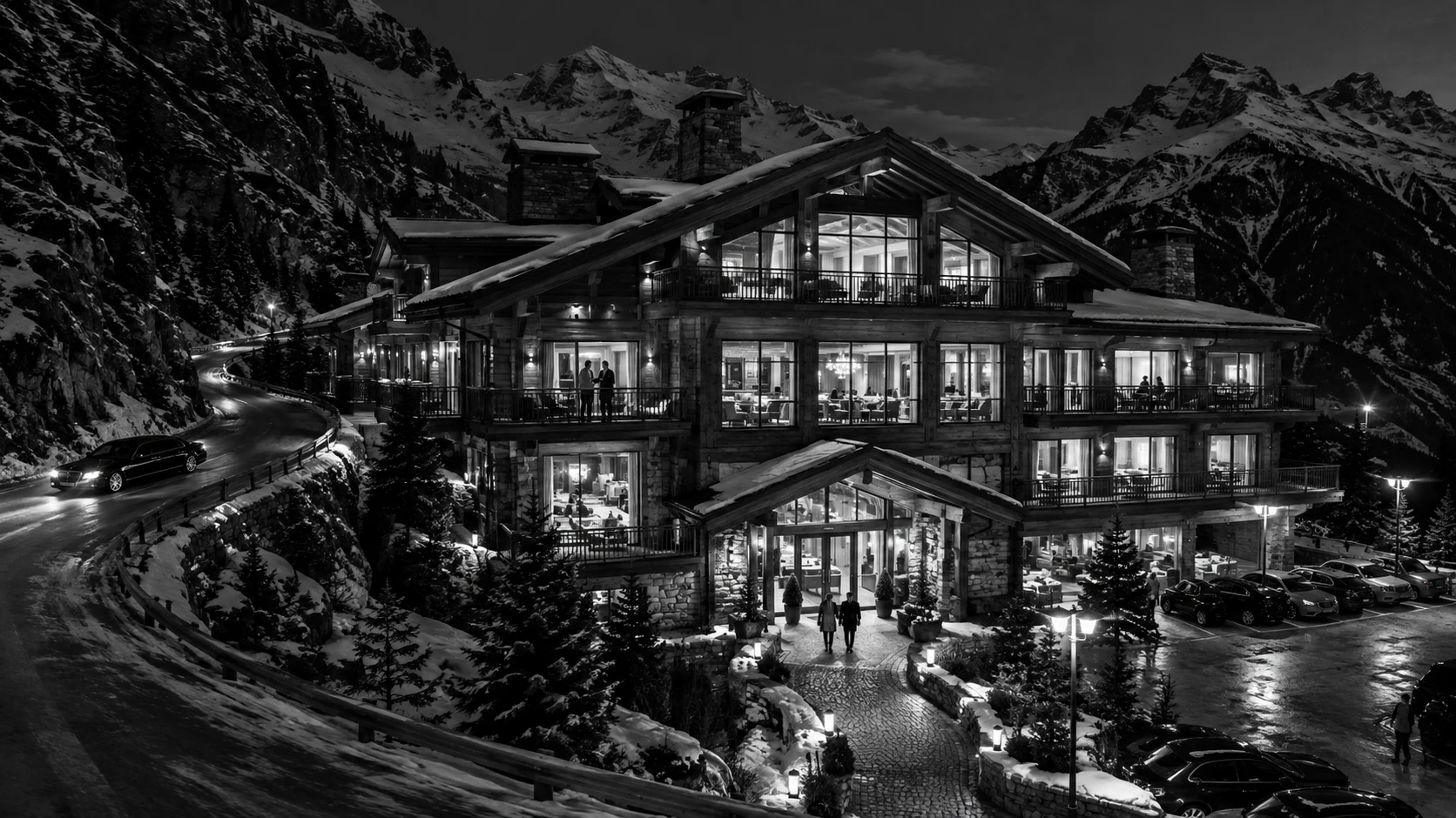 A Swiss chalet resort glows above a winding mountain road at night