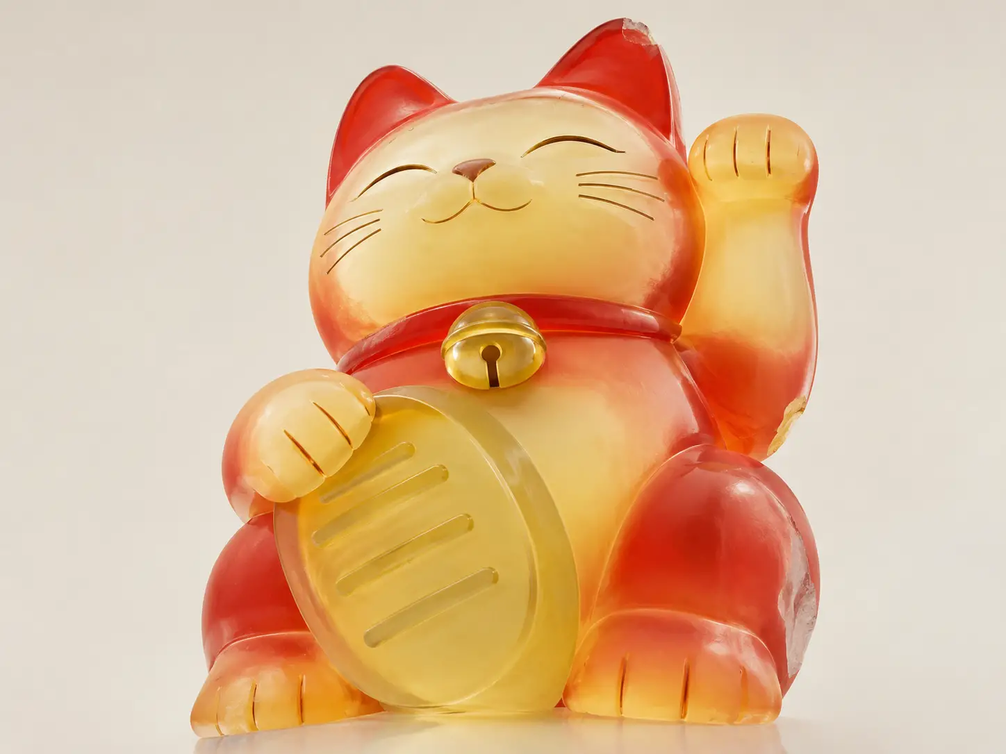 A red and yellow beckoning cat figure against a neutral background