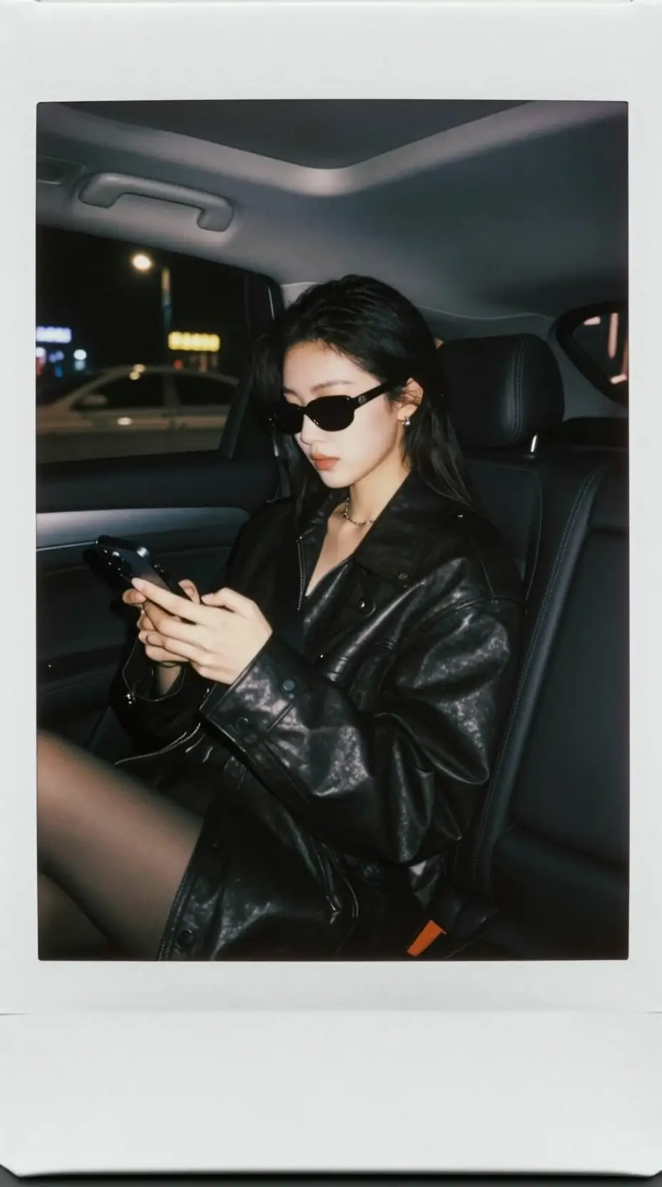 A young woman checks her phone inside a luxury car at night