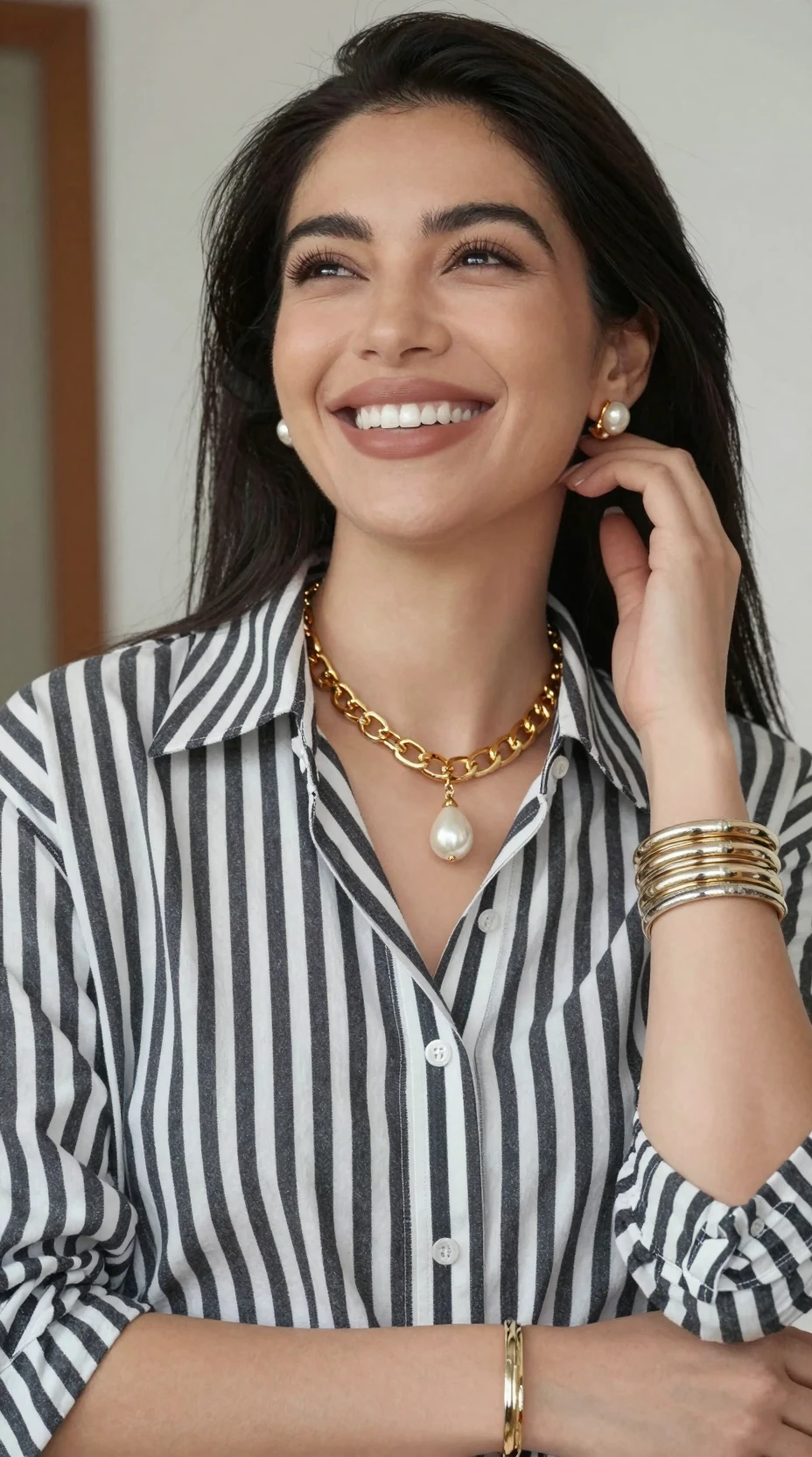 Una mujer sonriente mira hacia arriba con una camisa a rayas y joyas doradas