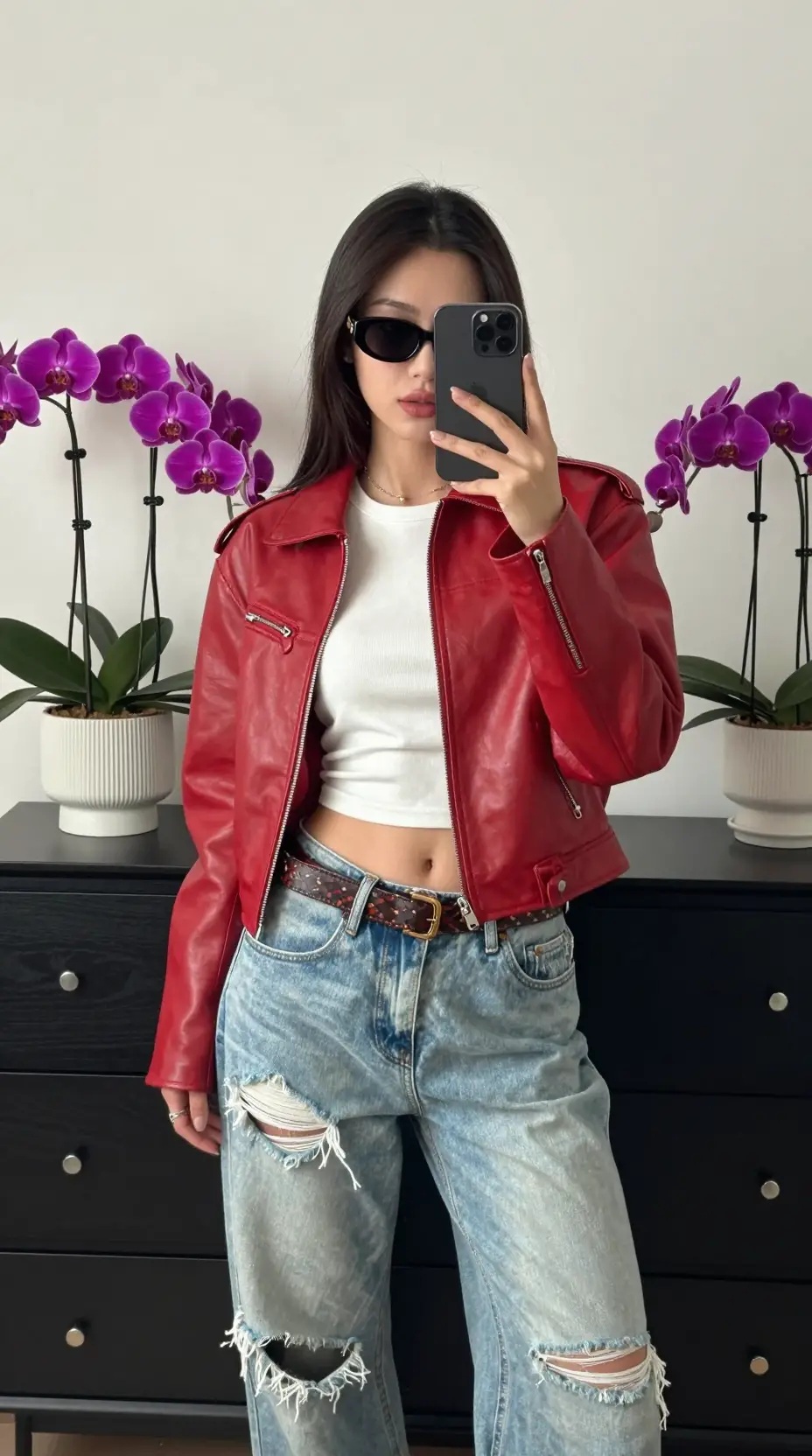 Una mujer se hace un elegante selfie en el espejo con una chaqueta de cuero roja