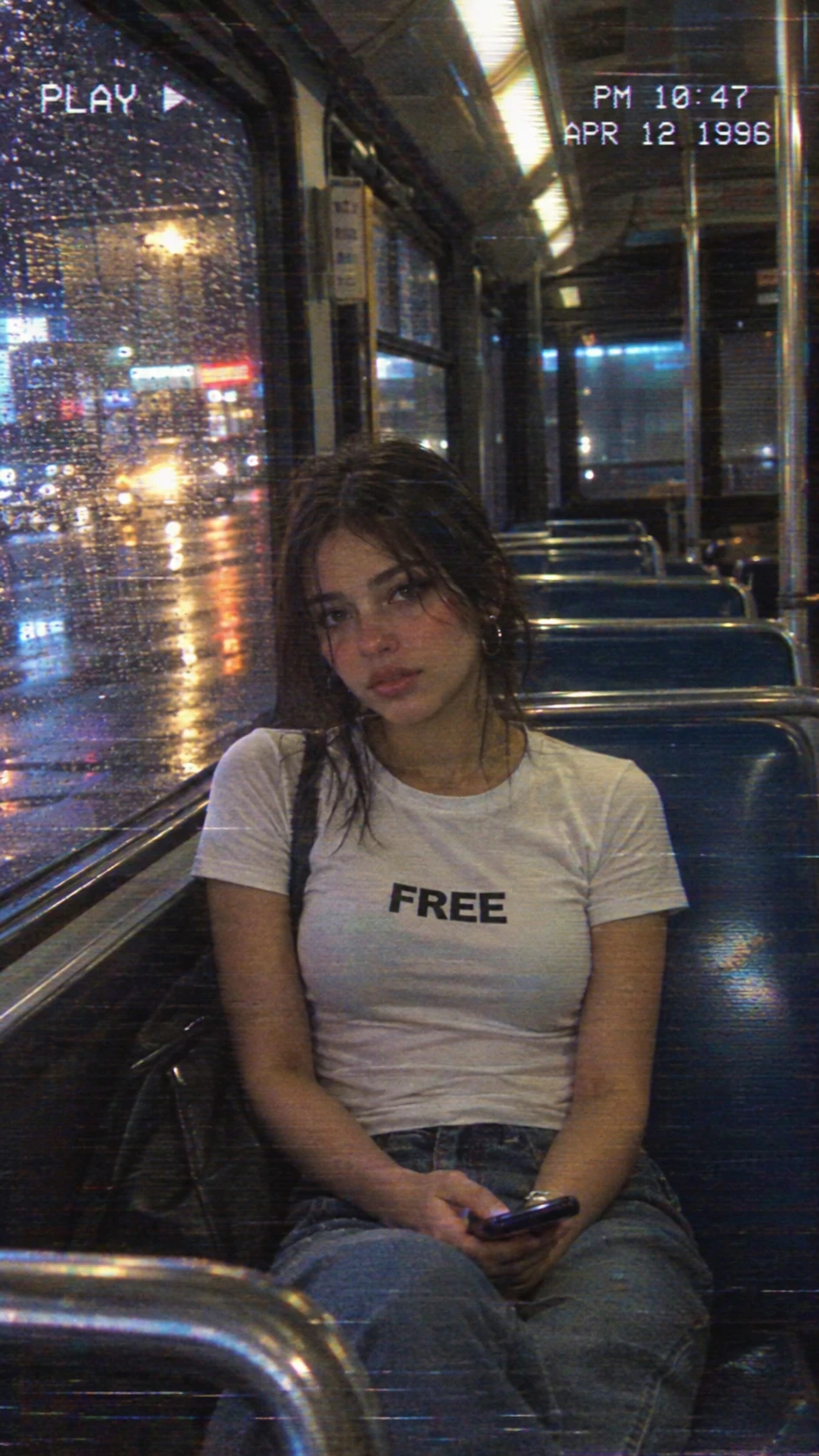 A young woman sits alone on a city bus at night