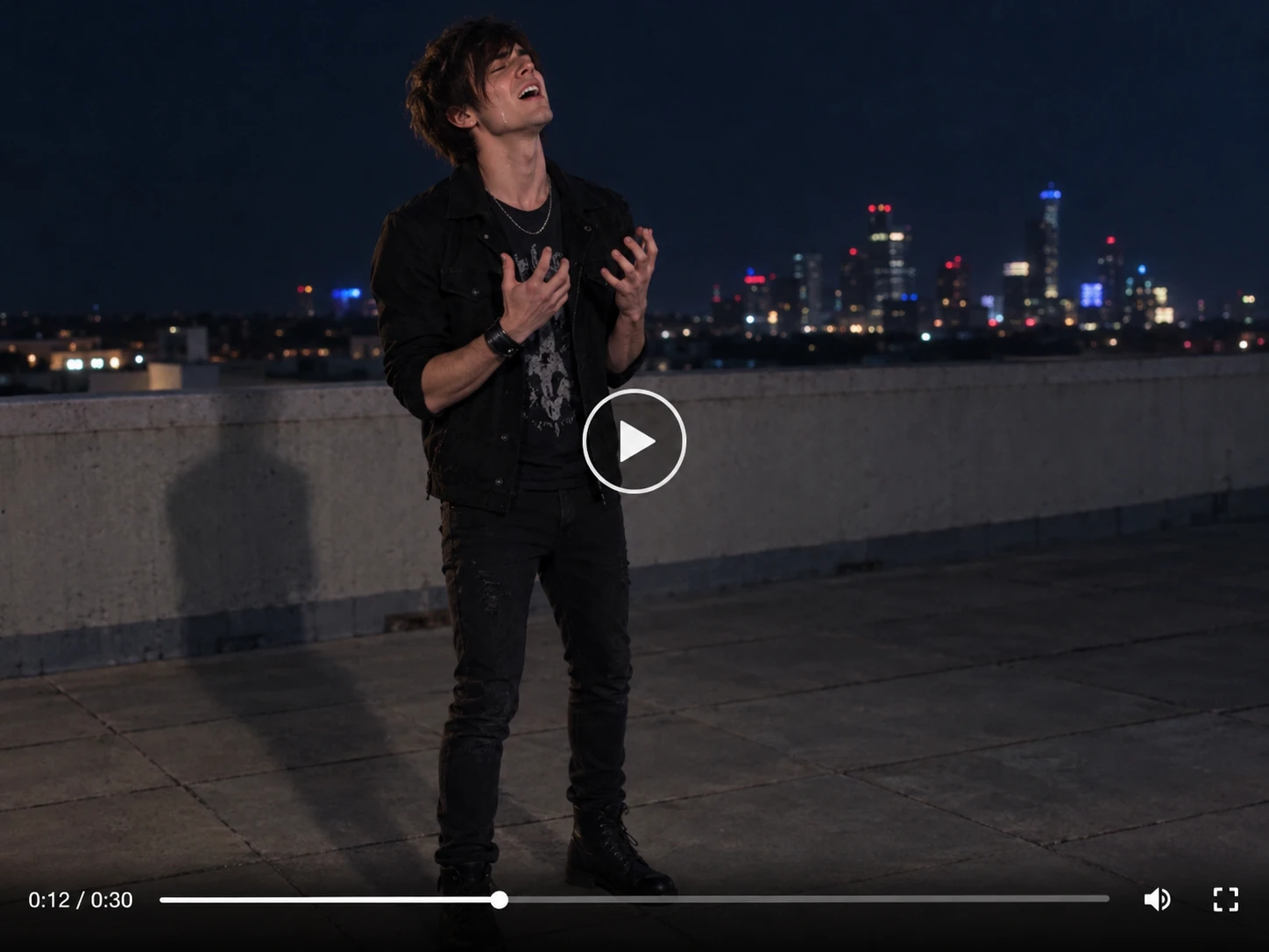 Un joven vestido de negro al estilo rock canta apasionadamente en una azotea por la noche, con las luces de la ciudad detrás.